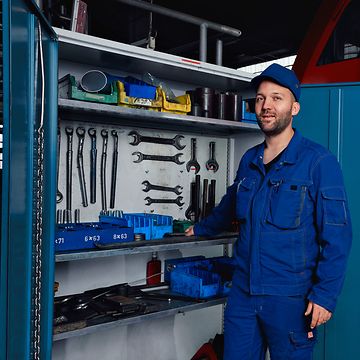 Ein Instandhaltungsmeister in Arbeitskleidung steht im Werk vor einem geöffneten Werkzeugschrank