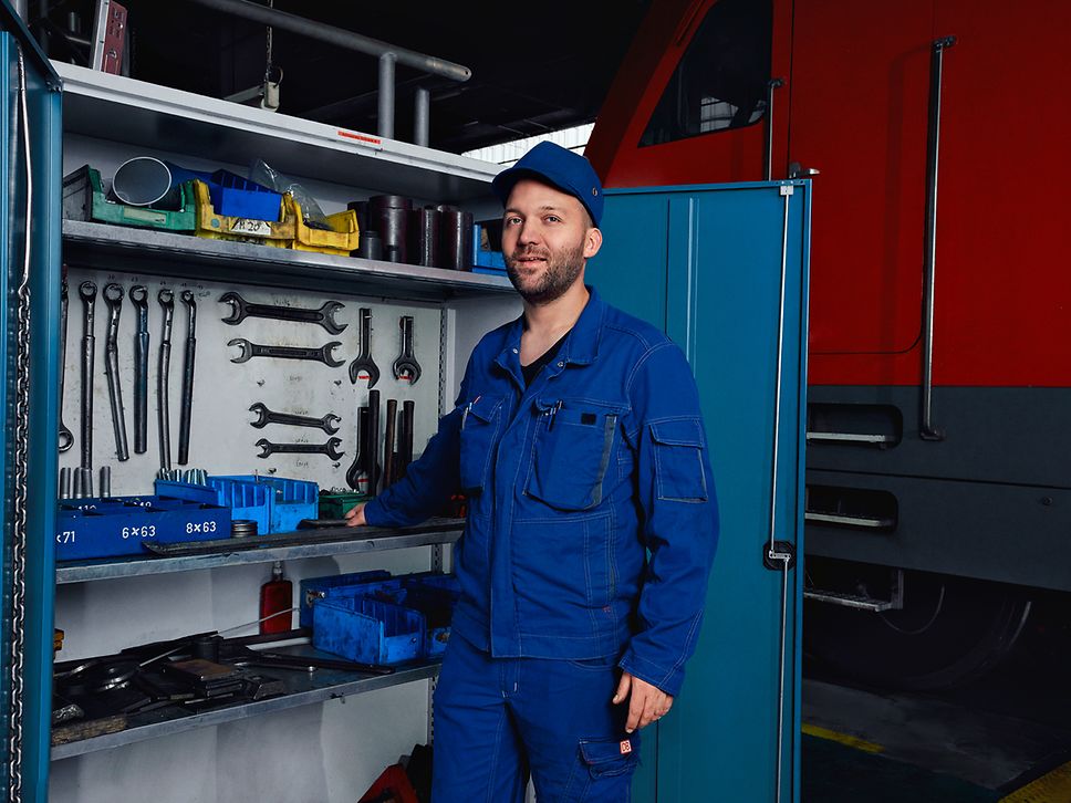 Ein Instandhaltungsmeister in Arbeitskleidung steht im Werk vor einem geöffneten Werkzeugschrank
