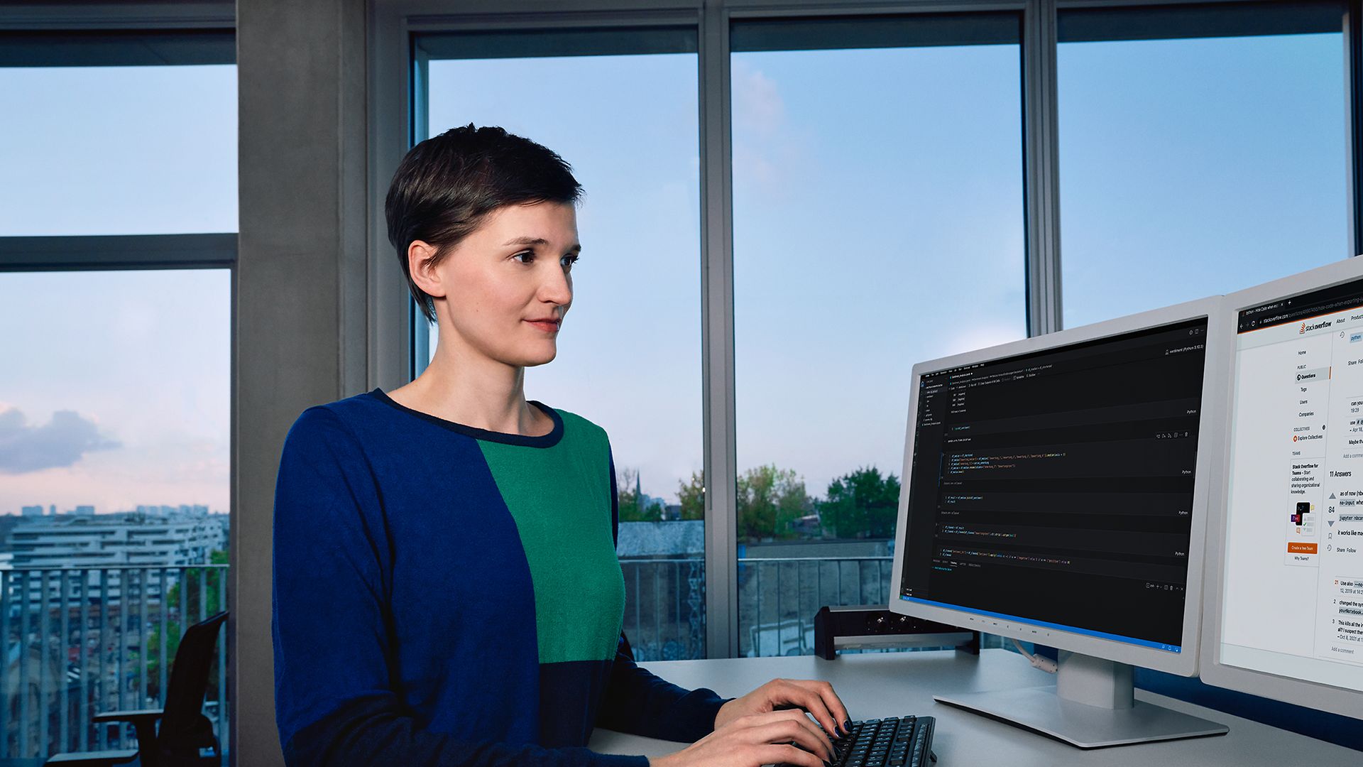 Eine Data Scientist steht in einem Bürogebäude am Schreibtisch und arbeitet am PC