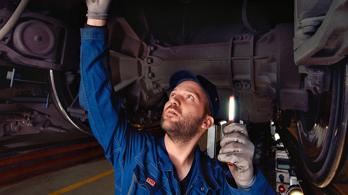 Ein Instandhaltungsmeister in Arbeitskleidung steht in der Wartungsgrube und kontrolliert die Radsätze