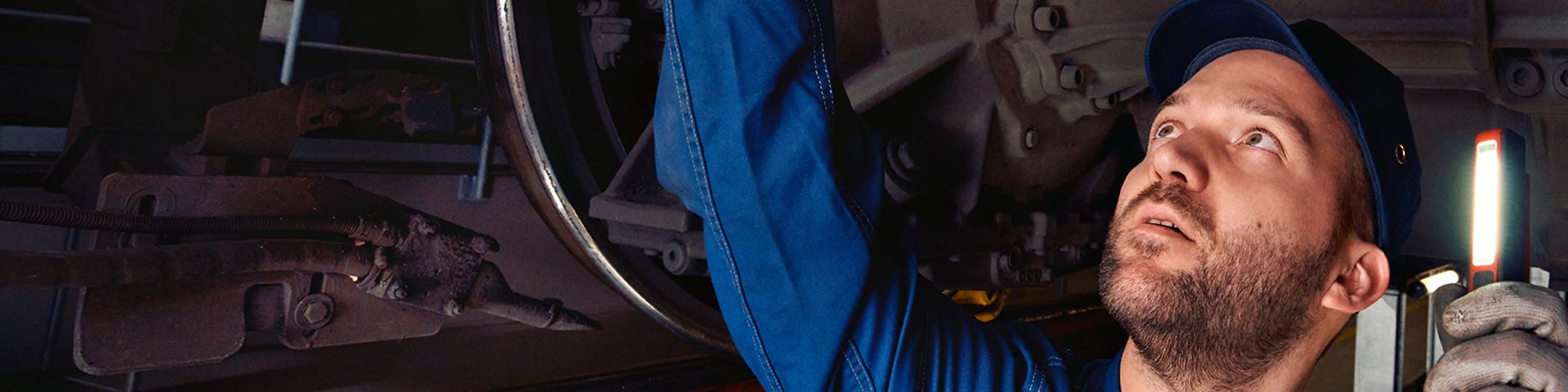 Ein Instandhaltungsmeister in Arbeitskleidung steht in der Wartungsgrube und kontrolliert die Radsätze