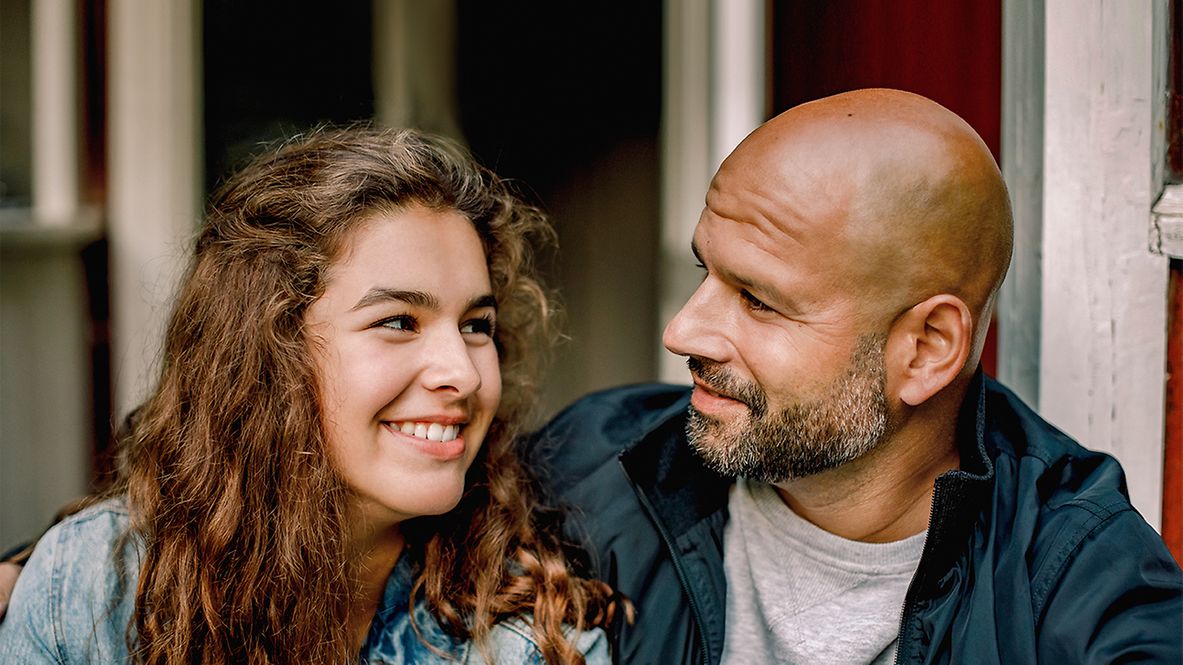Vater und Tochter sehen sich lächeln an