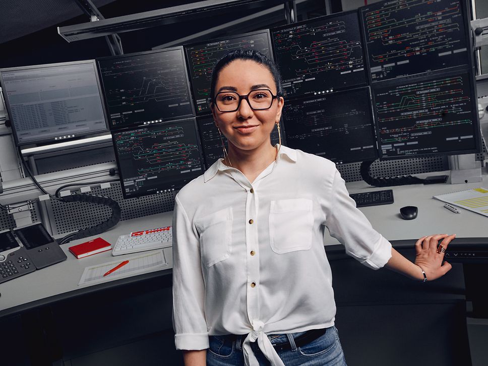 Eine Zugverkehrssteuerin sitzt vor den acht Bildschirmen eines Elektronischen Stellwerkes