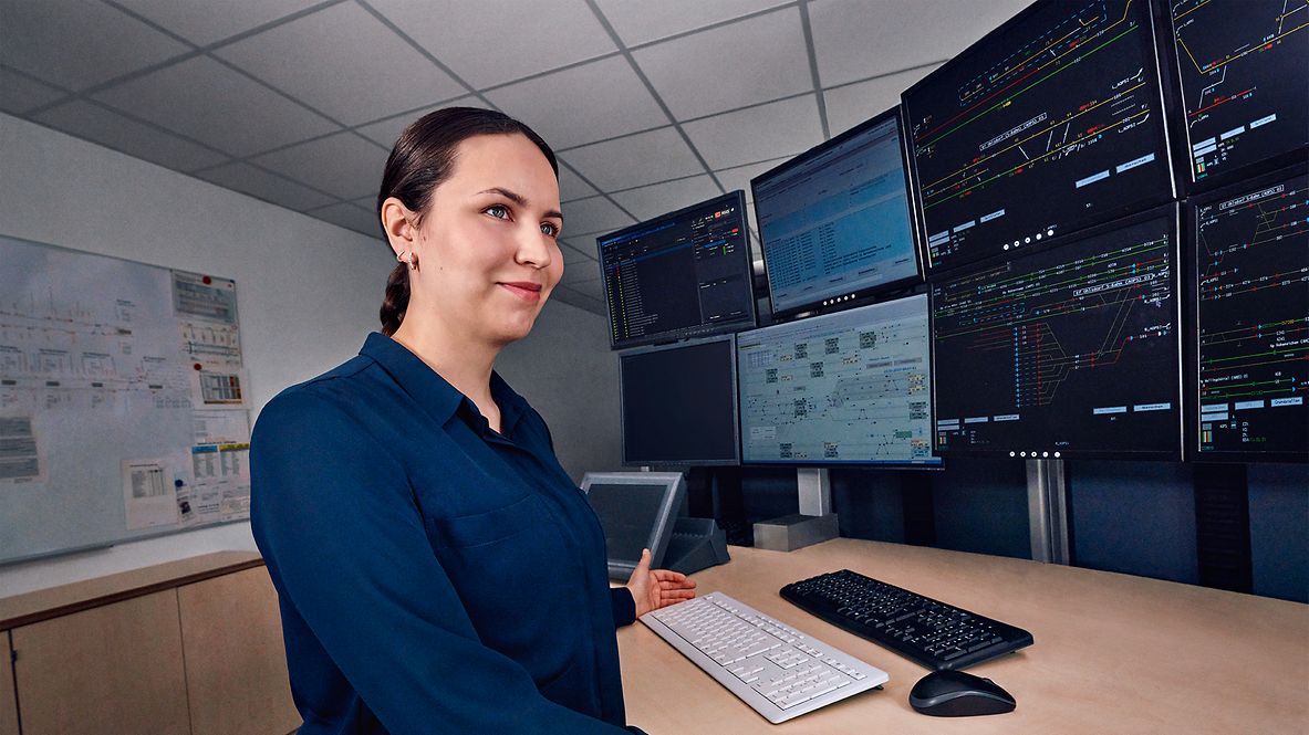 Eine Fahrdienstleiterin arbeitet an acht Bildschirmen des Elektronischen Stellwerks