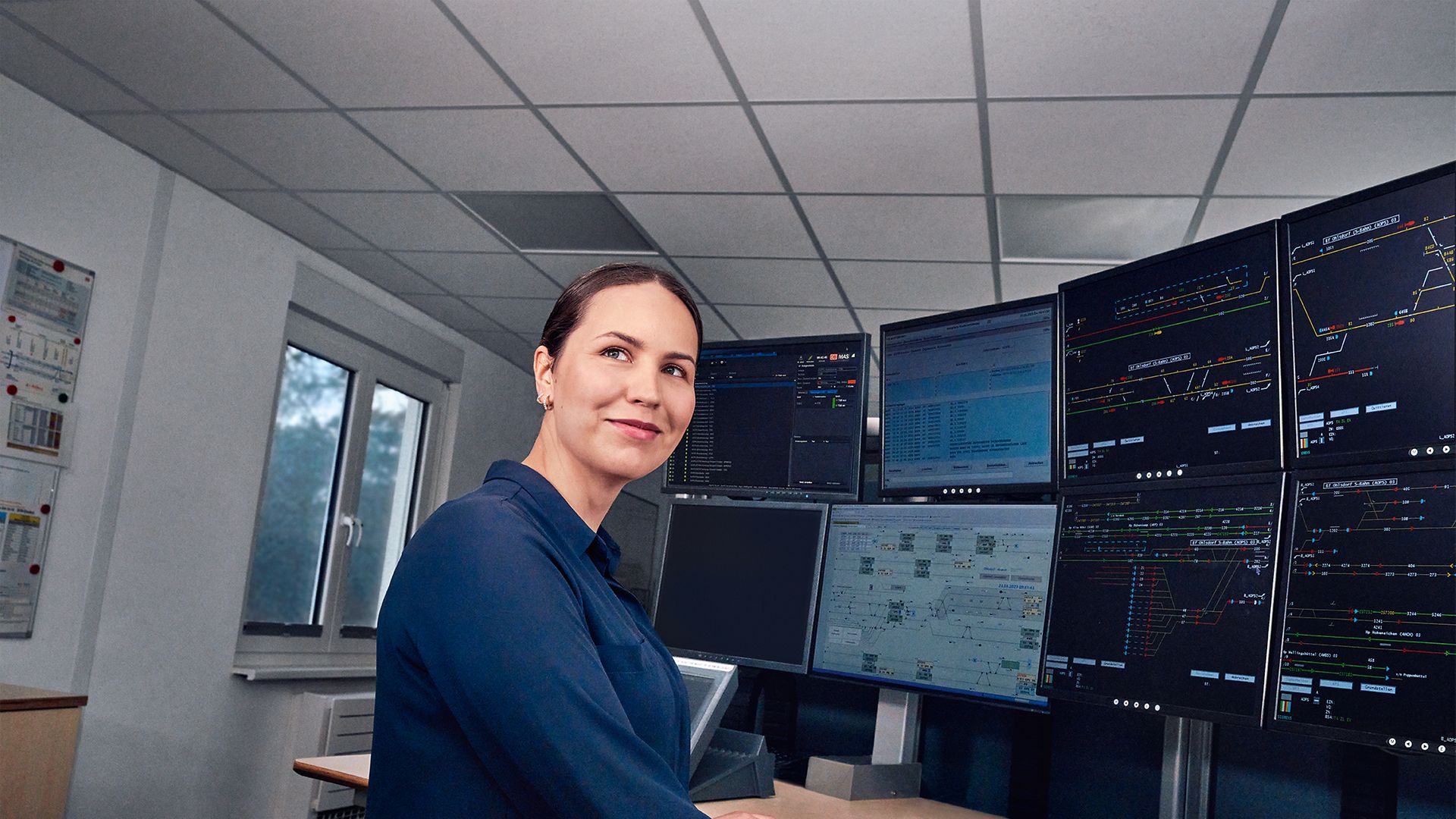 Eine Fahrdienstleiterin arbeitet an acht Bildschirmen des Elektronischen Stellwerks