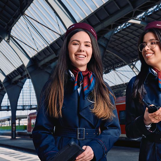 Zwei Auszubildende zur Kauffrau für Verkehrsservice stehen am Bahnsteig eines Bahnhofes