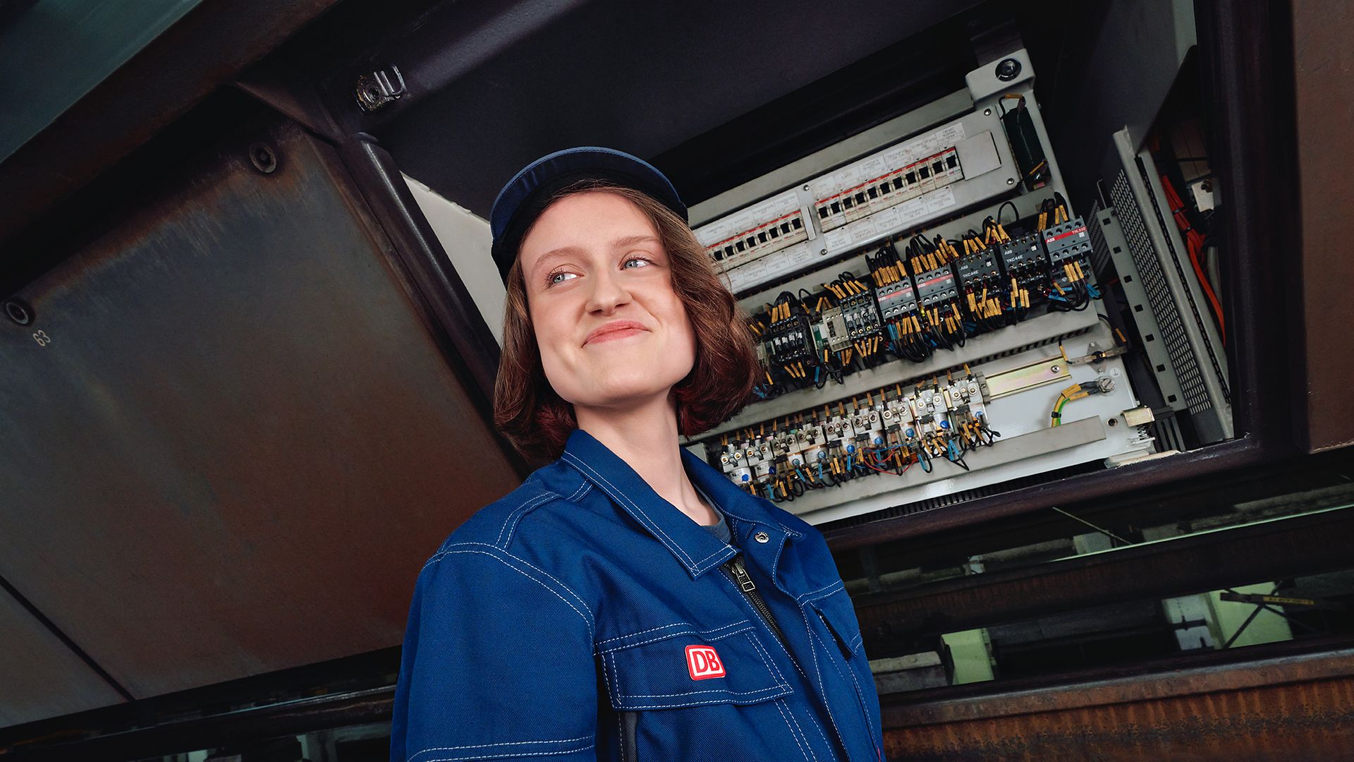 Eine Auszubildende in der Instandhaltung steht vor einem Relaisschrank