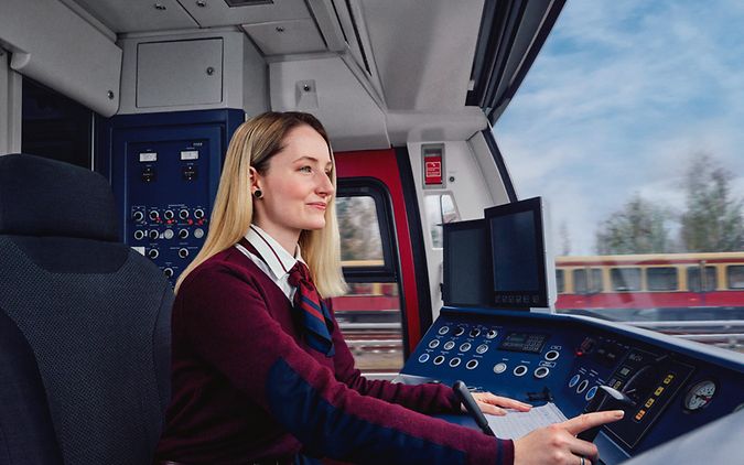 Eine Auszubildende zur Lokführerin sitzt im Führerstand einer S-Bahn und steuert den Zug