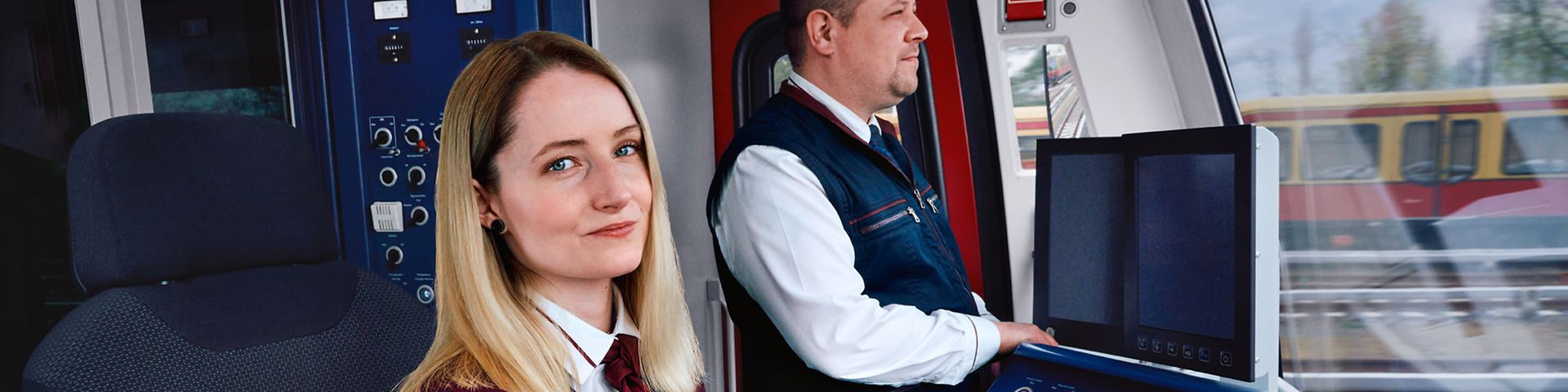 Eine Auszubildende zur Lokführerin sitzt neben einem Ausbilder im Führerstand einer S-Bahn und steuert den Zug