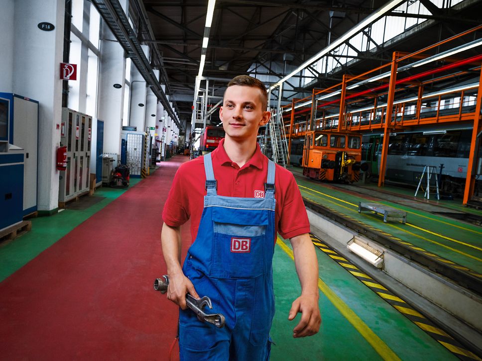 Ein Instandhalter mit Werkzeug in der Hand läuft in Arbeitskleidung durch ein Instandhaltungswerk