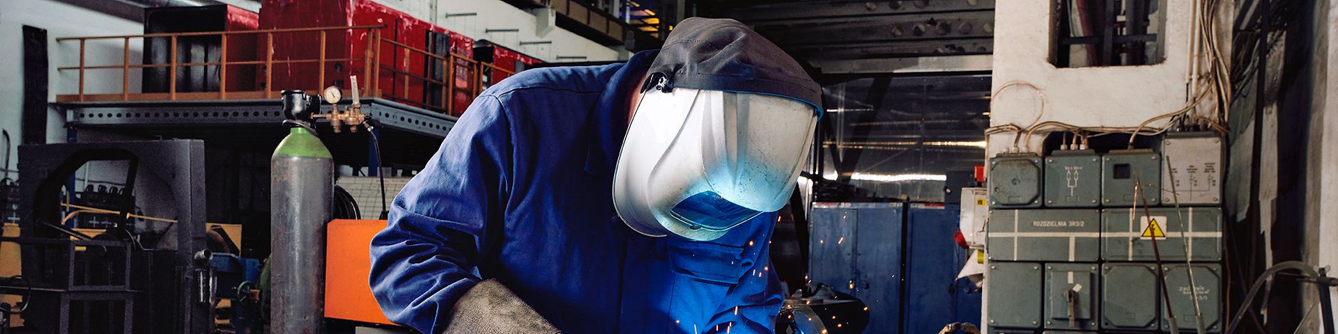 Ein Industriemechaniker arbeitet mit Schweißermaske und Schweißgerät in einer Werkstatt