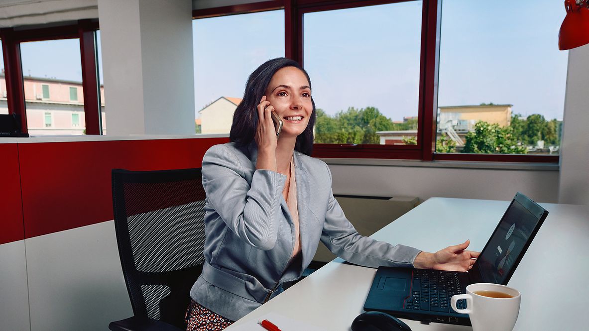 Eine kaufmännische Mitarbeiterin sitzt im Büro und telefoniert