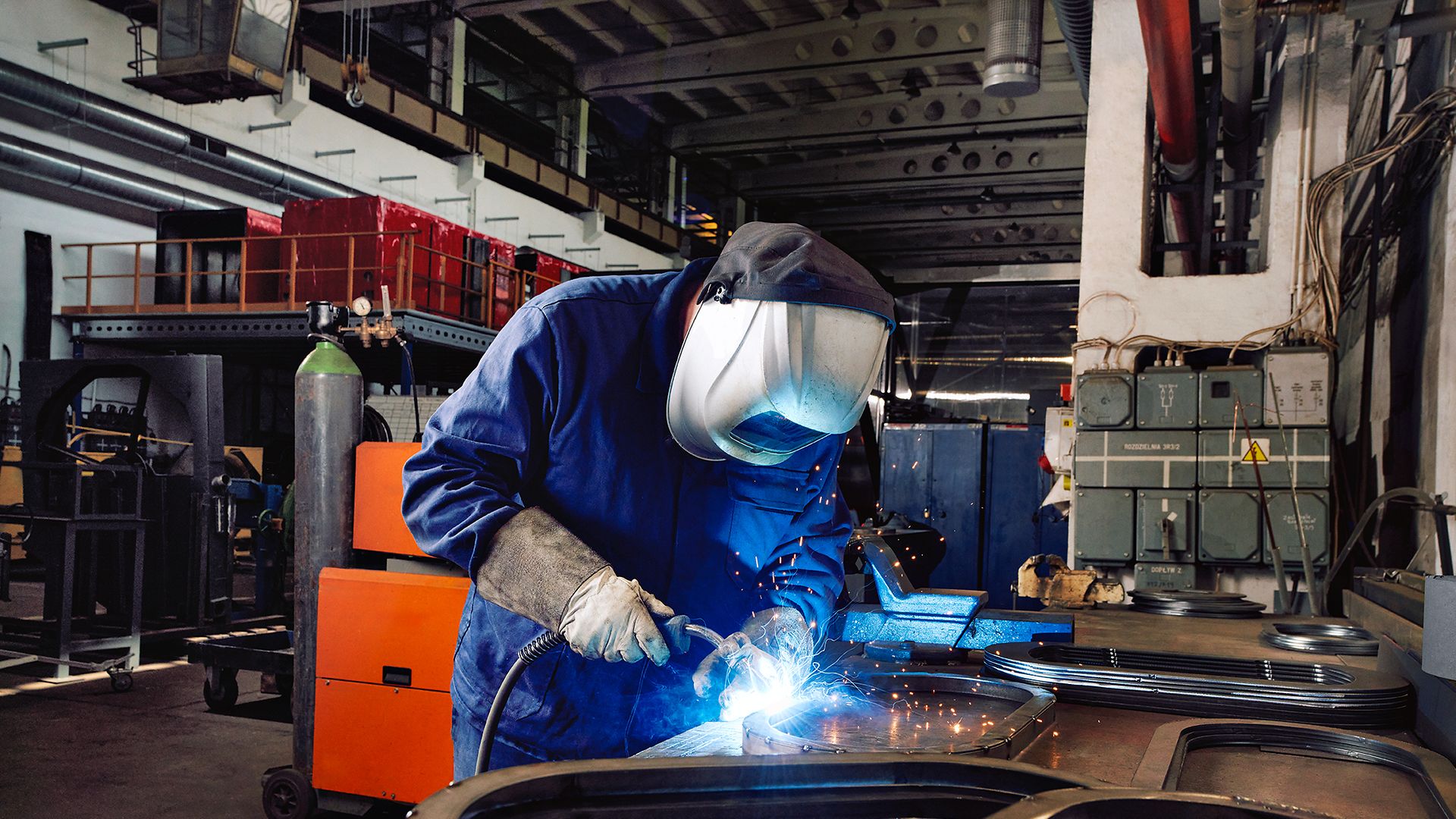 Ein Industriemechaniker arbeitet mit Schweißermaske und Schweißgerät in einer Werkstatt