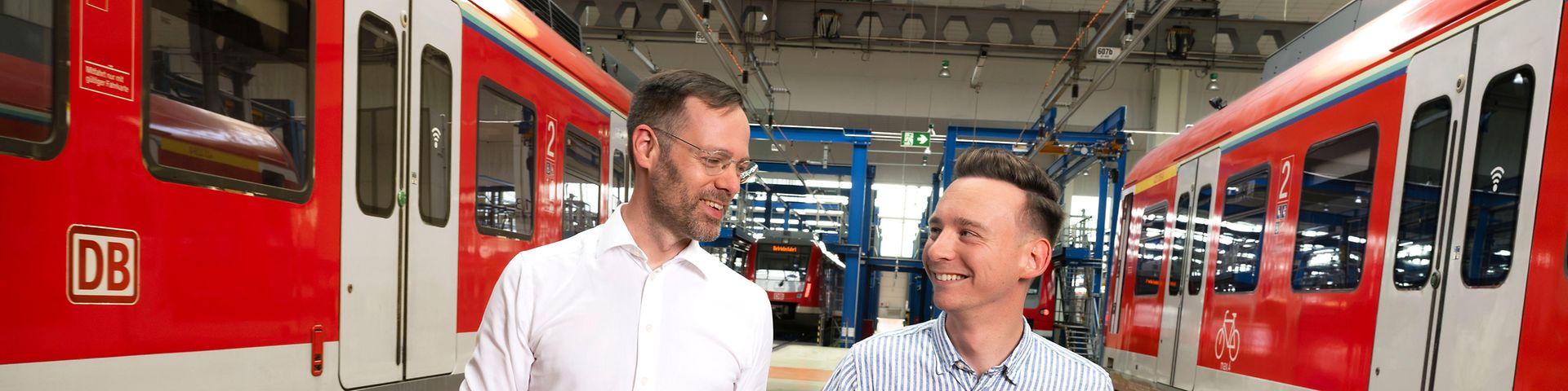 Zwei Consultant Manager durchqueren eine Werkhalle für S-Bahnen