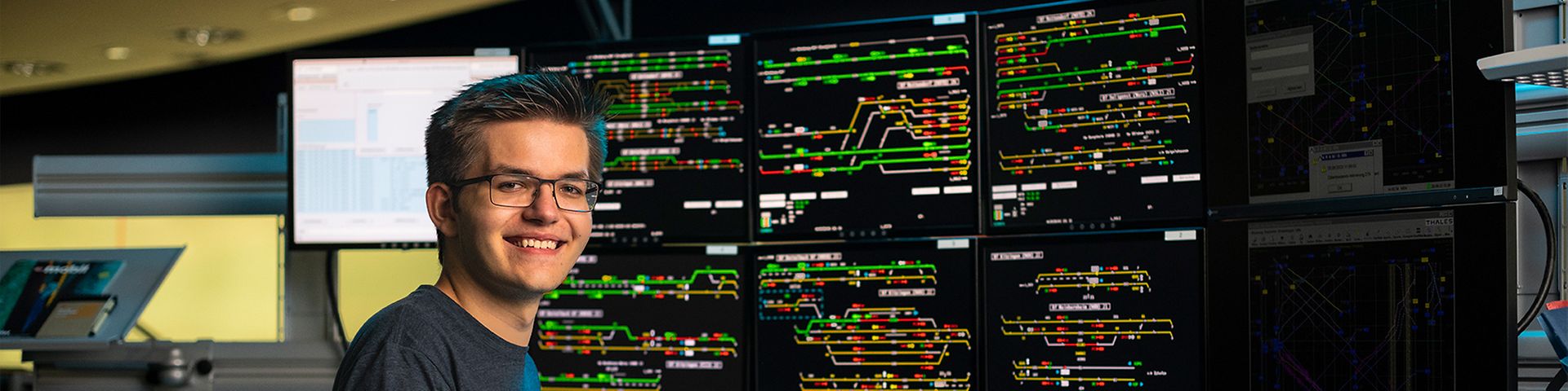 Ein Auszubildender zum Zugverkehrssteuerer arbeitet an den Bildschirmen des Elektronischen Stellwerks