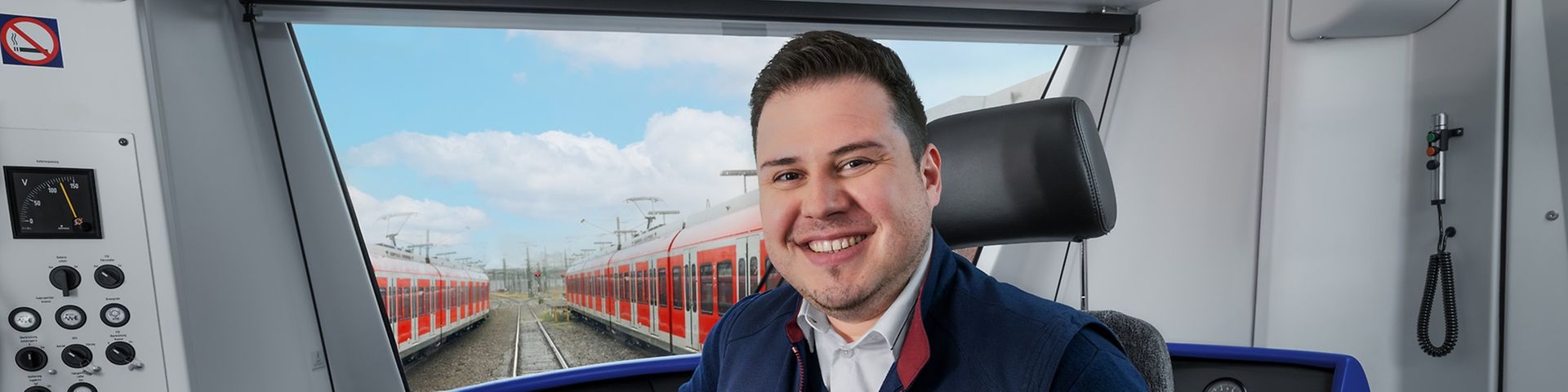 Ein Lokführer sitzt im Führerstand einer haltenden S-Bahn und hält ein Tablet in der Hand