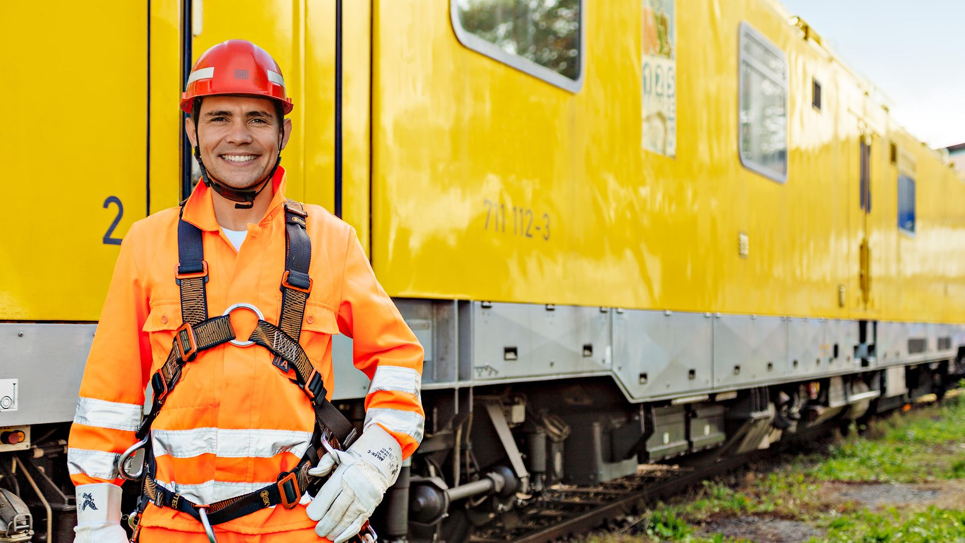 Dmitry Gladchenko, Elektriker bei der Deutschen Bahn, in Arbeitskleidung vor einem Zug.