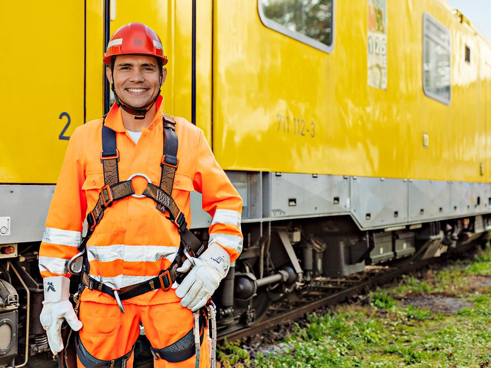 Dmitry Gladchenko, Elektriker bei der Deutschen Bahn, in Arbeitskleidung vor einem Zug.