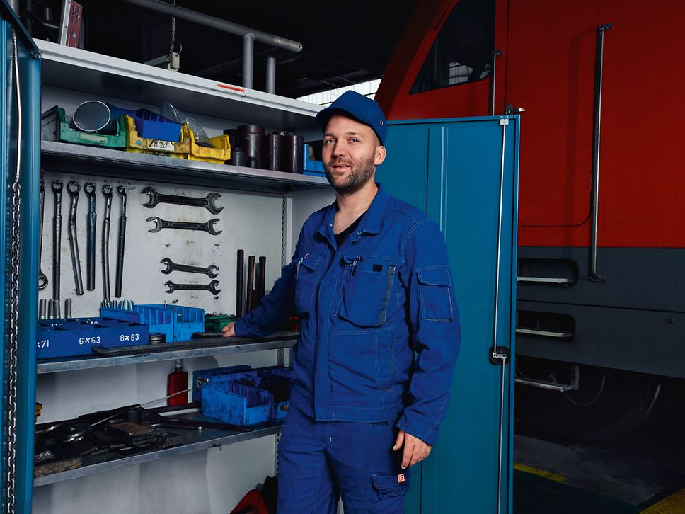 Ein Instandhaltungsmeister in Arbeitskleidung steht im Werk vor einem geöffneten Werkzeugschrank