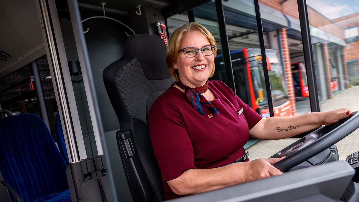 Eine Busfahrerin sitzt am Steuer und lenkt einen Bus