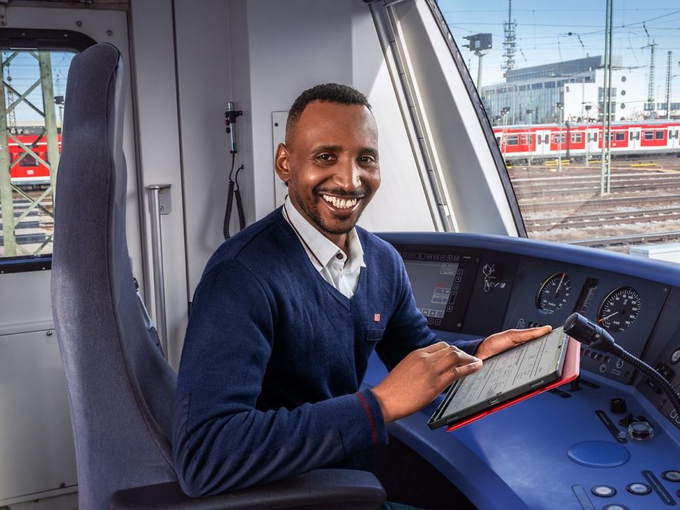 Ein Lokführer der S-Bahn München sitzt mit einem Tablet in der Hand im Führerstand