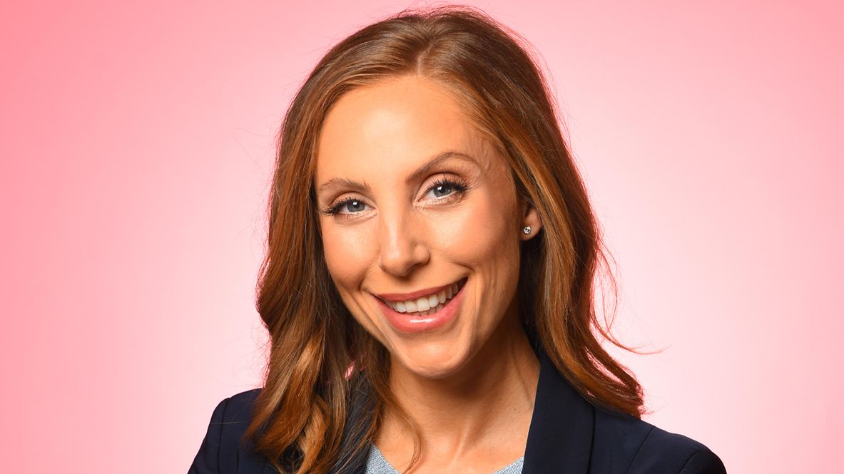 Porträtfoto von Timo Simon, trägt einen beigen Anzug, steht lächelnd in der Natur, hat die Arme verschränkt