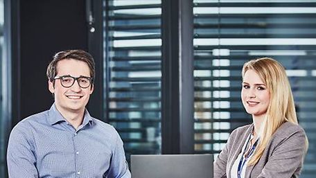 Two young employees working for DB Schenker standing in the office