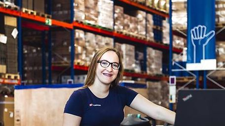 A young female doing an apprenticeship in warehouse logistics at DB Schenker is standing in a warehouse
