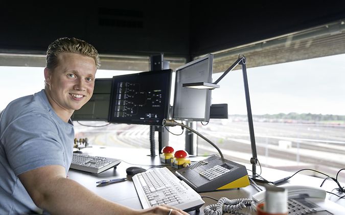 Ein junger Fahrdienstleister arbeitet am Computer am Bahnhof.