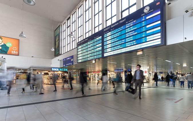Eine Reisendeninformation Anzeigetafel im Düsseldorfer Hauptbahnhof mit Reisenden