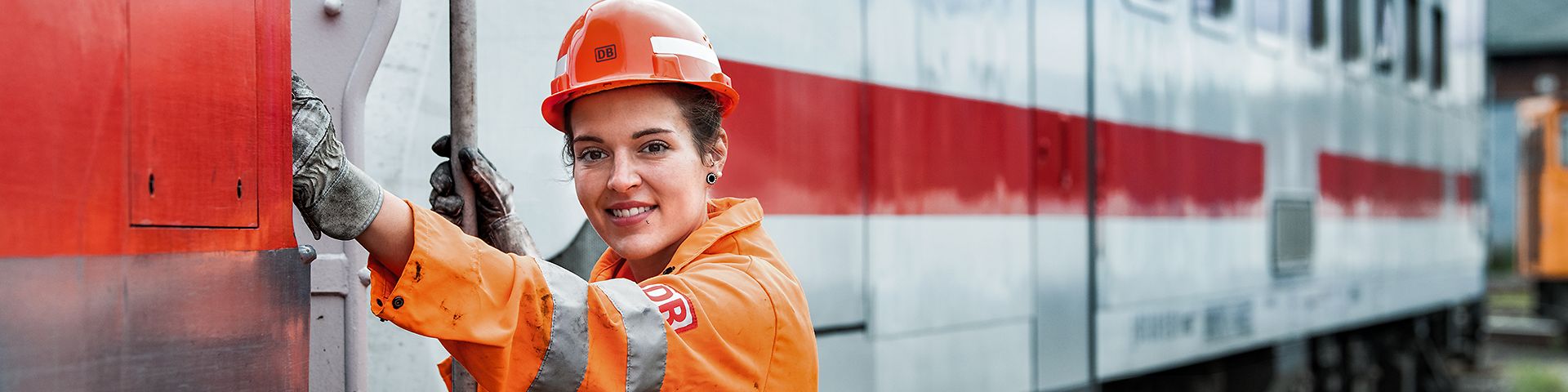 Eine Lokrangierführerin in Warnkleidung und mit Schutzhelm steigt in den Führerstand