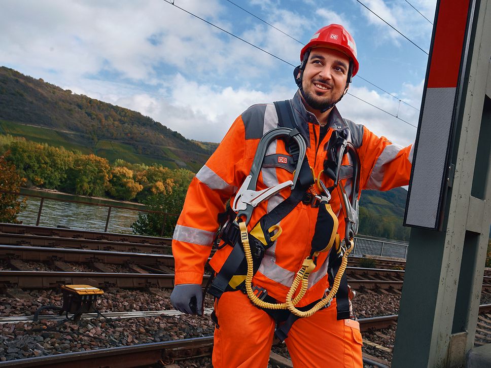 Ein Signalmechaniker in Warnkleidung und mit Schutzhelm steht auf einer Hebebühne