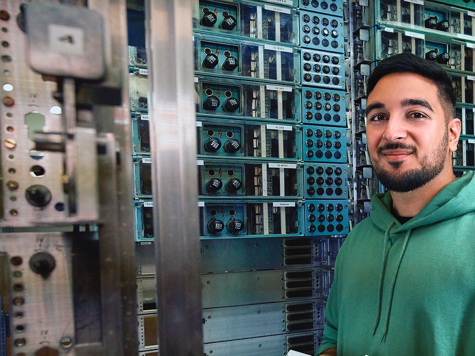 Ein Signalmechaniker steht vor einem Relaisschrank und hält ein elektronisches Diagnosegerät in der Hand