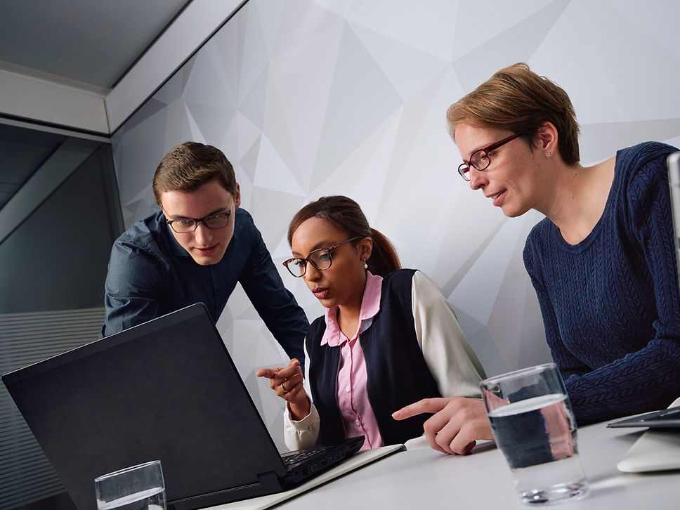 Ein Team von IT-Mitarbeitern sitzt vor einem Bildschirm und diskutiert