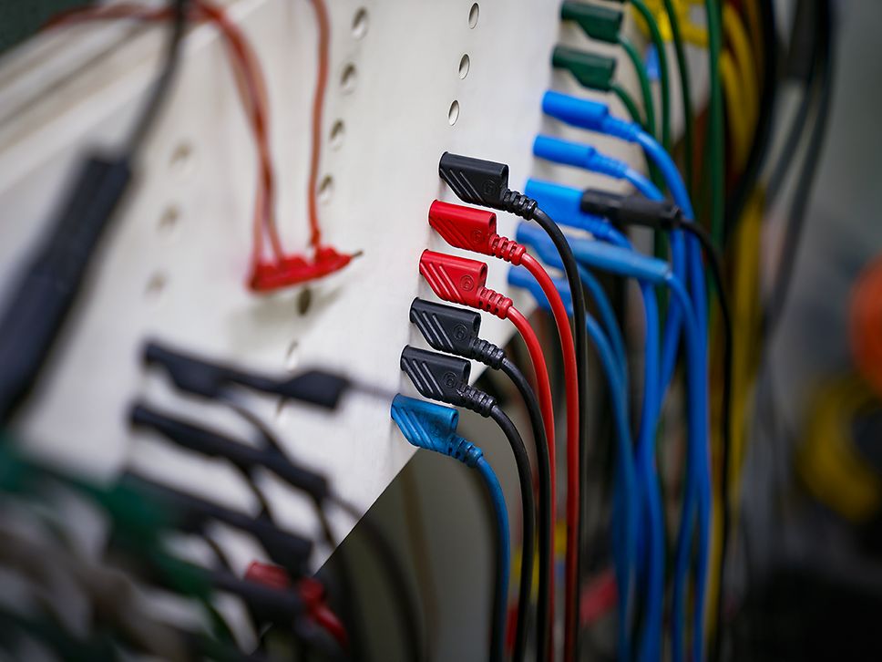 Rote, blaue und schwarze Stecker stecken in einer Steckerleiste