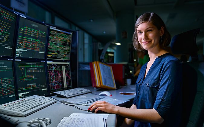 Eine Auszubildende zur Fahrdienstleiterin sitzt an den acht Bildschirmen eines Elektronischen Stellwerkes