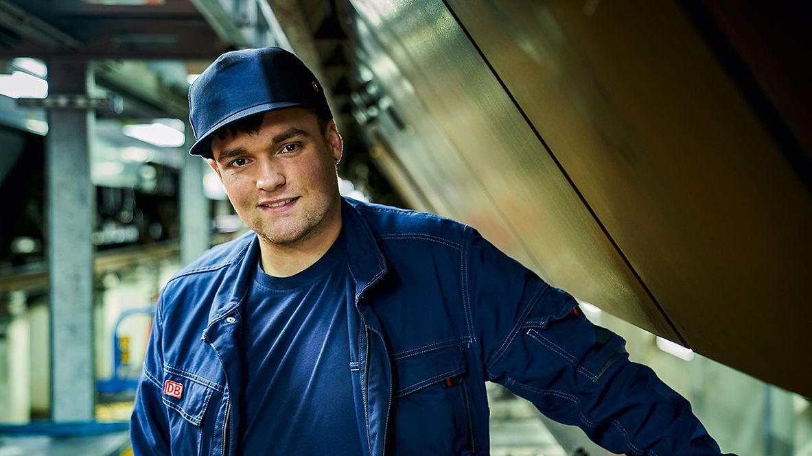 Ein Elektriker in Arbeitsbekleidung steht im Bahnbetriebswerk