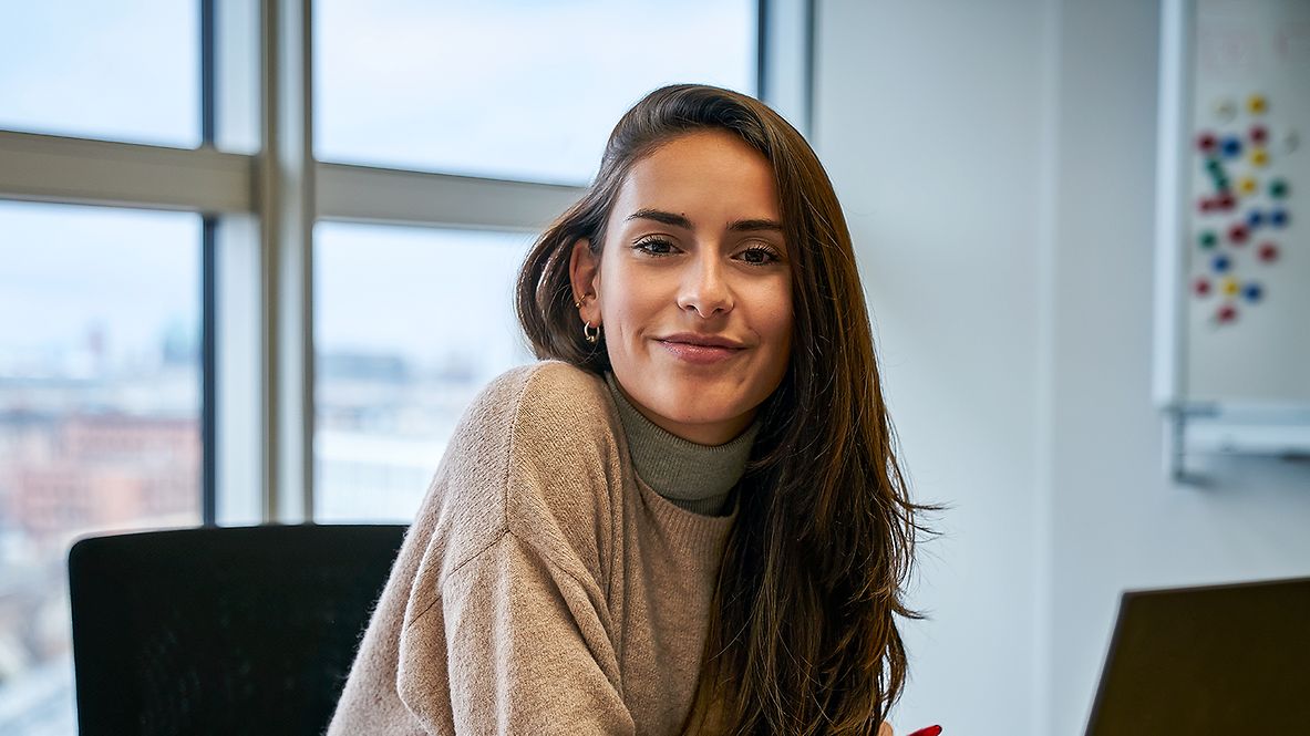 Eine Praktikantin sitzt in einem Büro am Schreibtisch