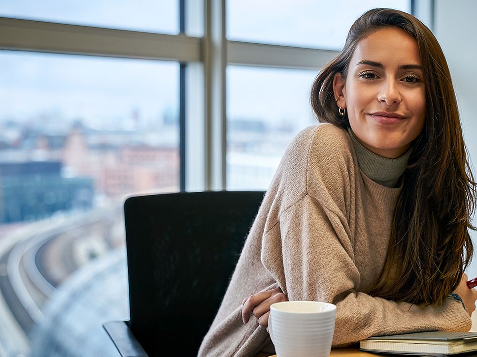 Eine Praktikantin sitzt in einem Büro am Schreibtisch