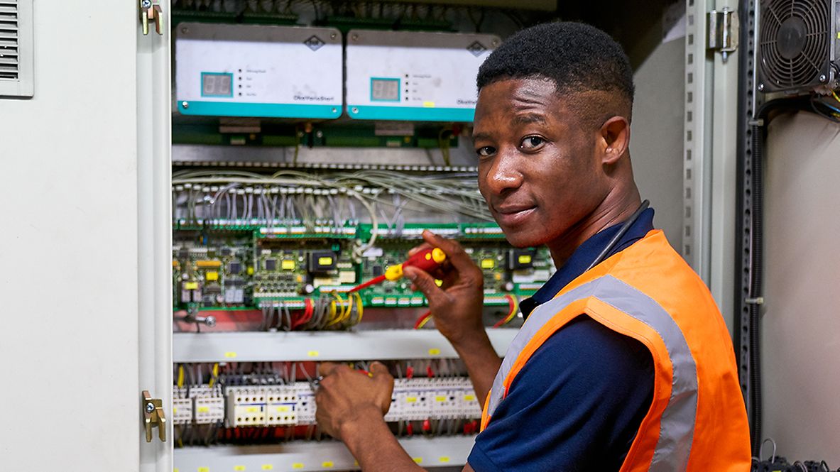 Ein Auszubildender zum Elektroniker für Betriebstechnik steht an einem Schutzrelaisschrank