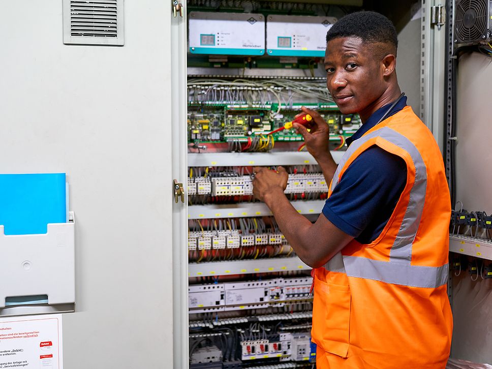 Ein Auszubildender zum Elektroniker für Betriebstechnik steht an einem Schutzrelaisschrank