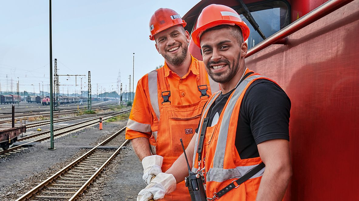 Zwei Lokrangierführer in Warnkleidung stehen vor dem Triebwagen