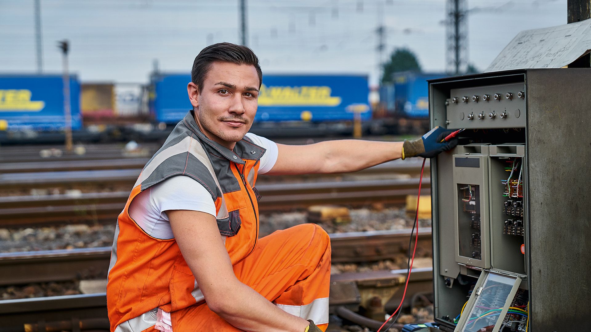 Ein Elektroniker für Leit- und Sicherungstechnik (LST) in Warnkleidung repariert Relais an der Strecke