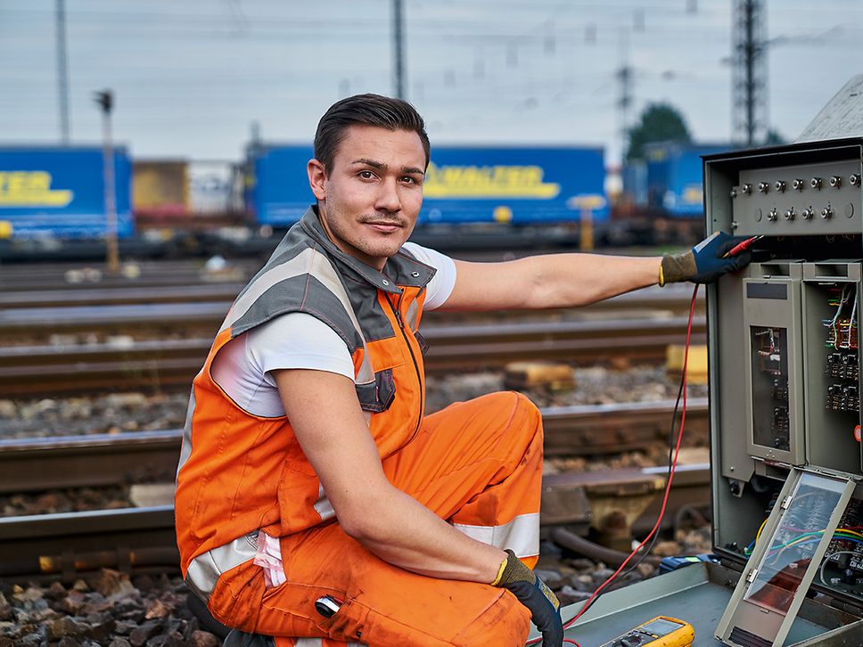 Ein Elektroniker für Leit- und Sicherungstechnik (LST) in Warnkleidung repariert Relais an der Strecke