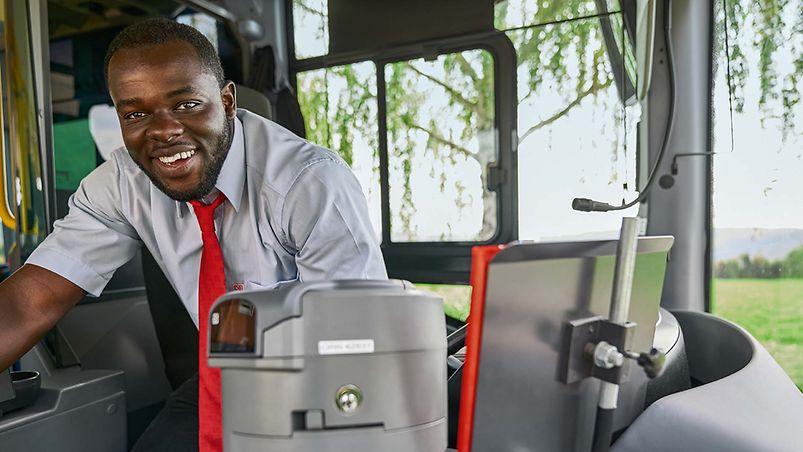 Ein Busfahrer in Unternehmensbekleidung sitzt auf dem Fahrersitz