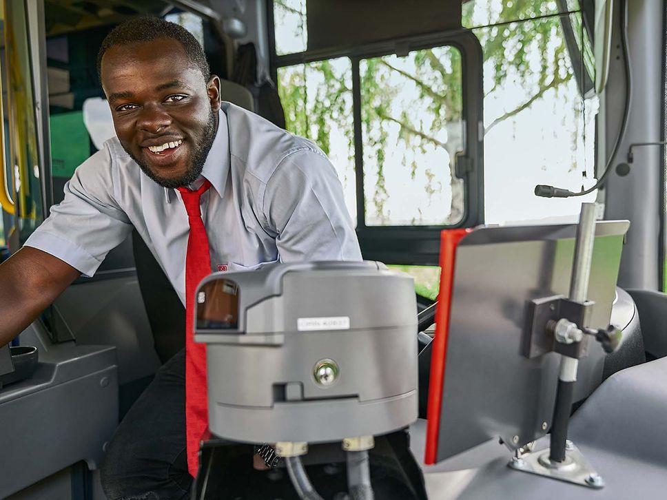 Ein Busfahrer in Unternehmensbekleidung sitzt auf dem Fahrersitz