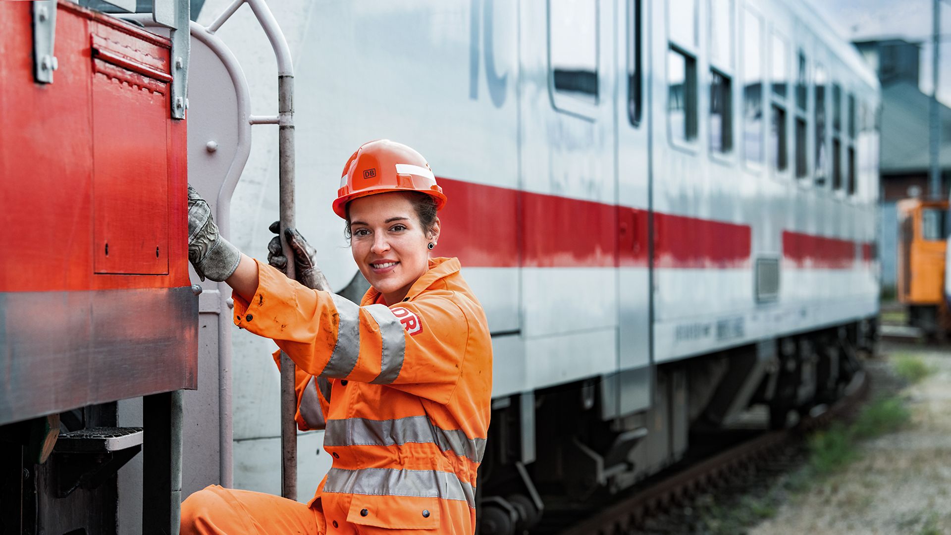 Eine Lokrangierführerin in Warnkleidung und mit Schutzhelm steigt in den Führerstand