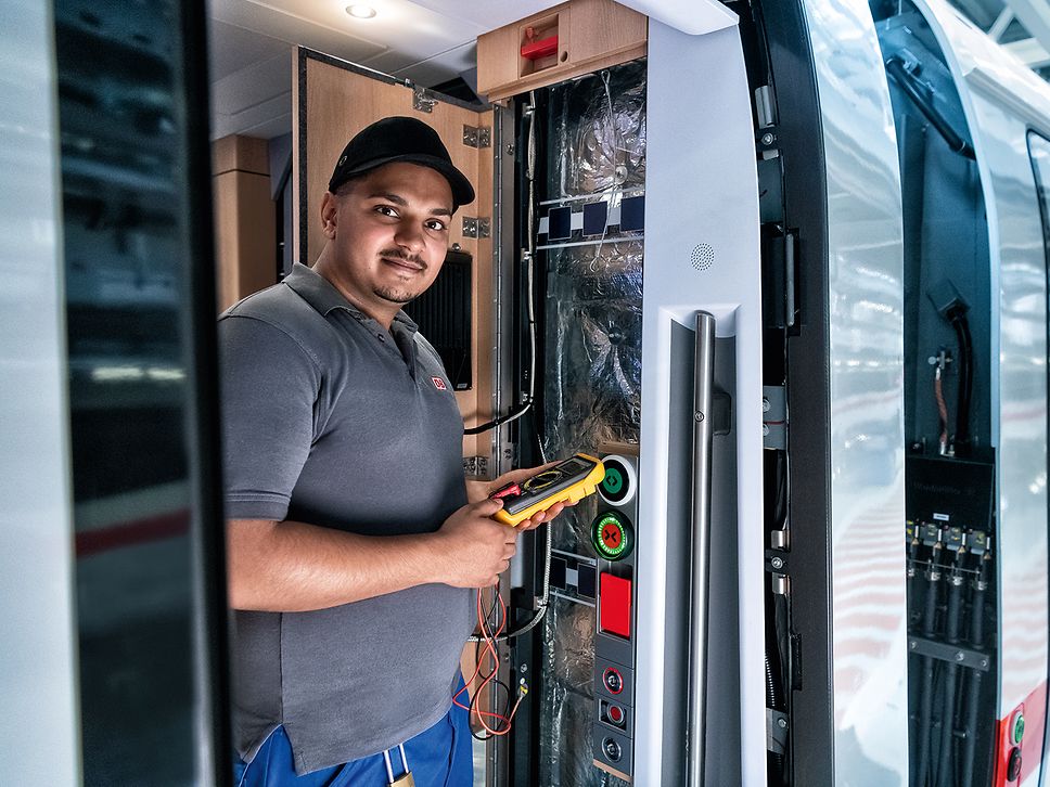 Ein Elektroniker liest die Bordelektronik einer Bildschirmanzeige im Gang eines Zuges aus