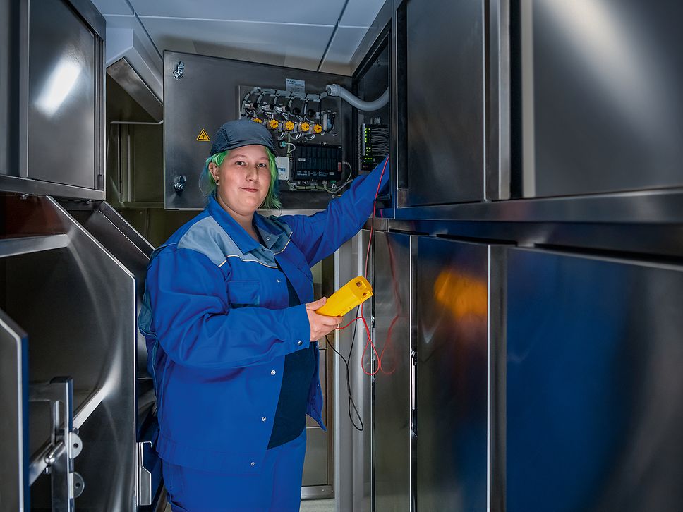 Eine Auszubildende zur Elektronikerin für Betriebstechnik prüft einen Relaisschrank