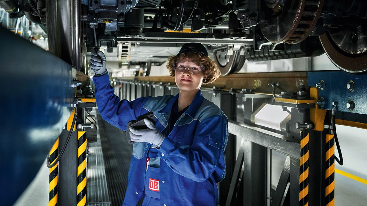 Eine Schlosserin in der Wartungsgrube prüft die Radsätze